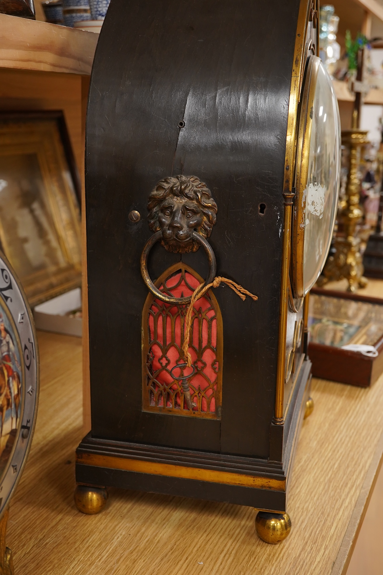 A Regency ebonised and brass inlaid lancet-shape bracket clock, with key and a painted pottery strut timepiece, largest 55cm high (2)
